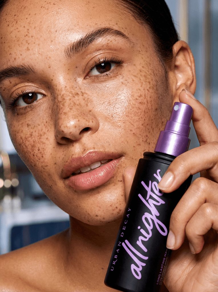 Woman with freckles holding a setting spray